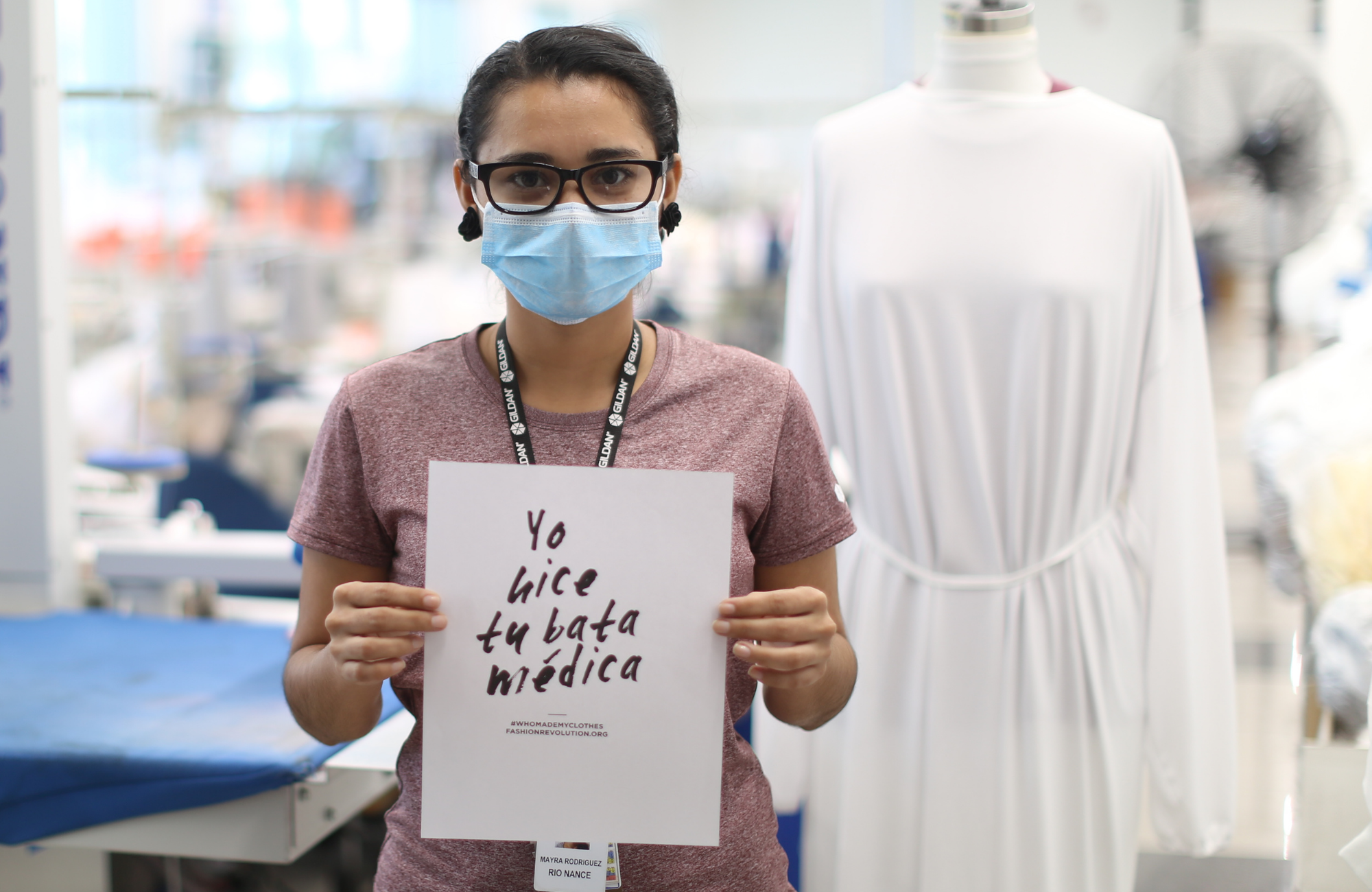 Employee Mayra Rodriguez holding a sign that reads “I made your medical gown” 