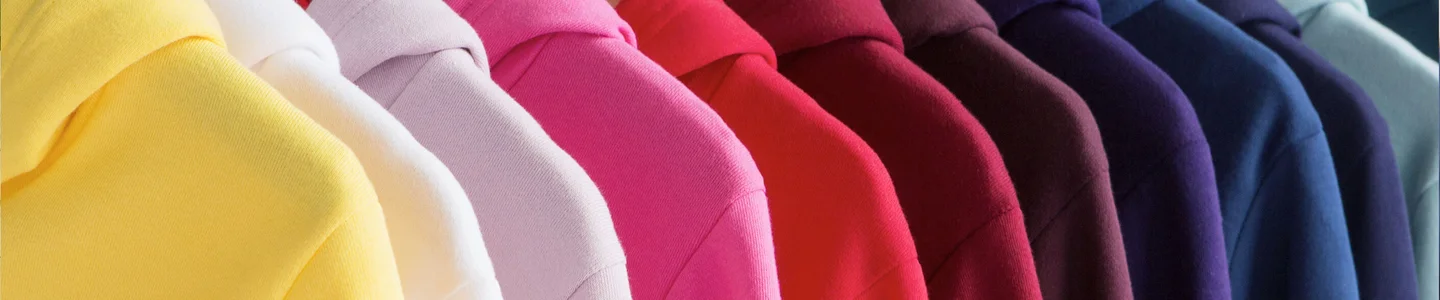 Vibrantly colored American Apparel™ sweaters are hung up on a rack.