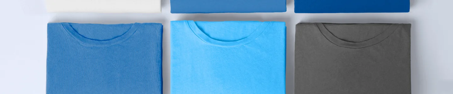 Folded blue and grey Gildan shirts on a white backdrop.