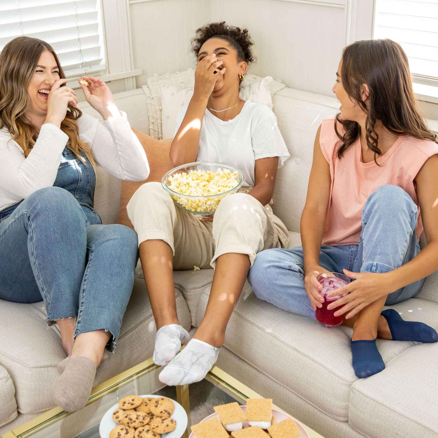 Trois femmes sont assises sur le canapé en riant et en mangeant tout en portant des chaussettes