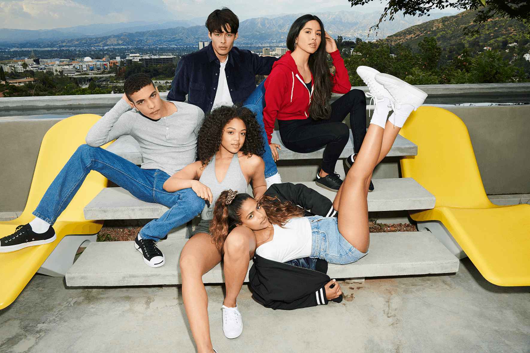 5 people are sitting outside looking at the camera, with the American Apparel™ logo in the center.