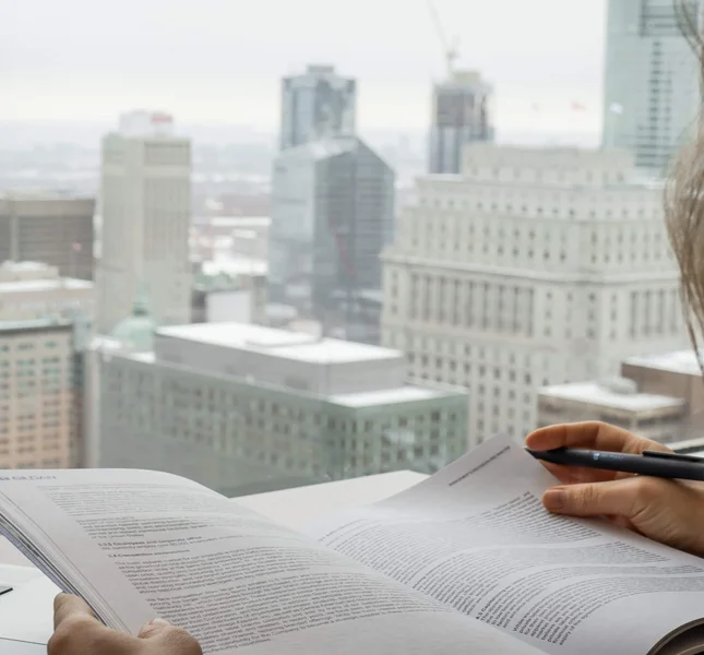 Female is looking through Gildan's annual report with the Montreal skyline in the background.