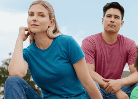 A woman sitting on bleachers outside wearing a blue shirt and jeans.