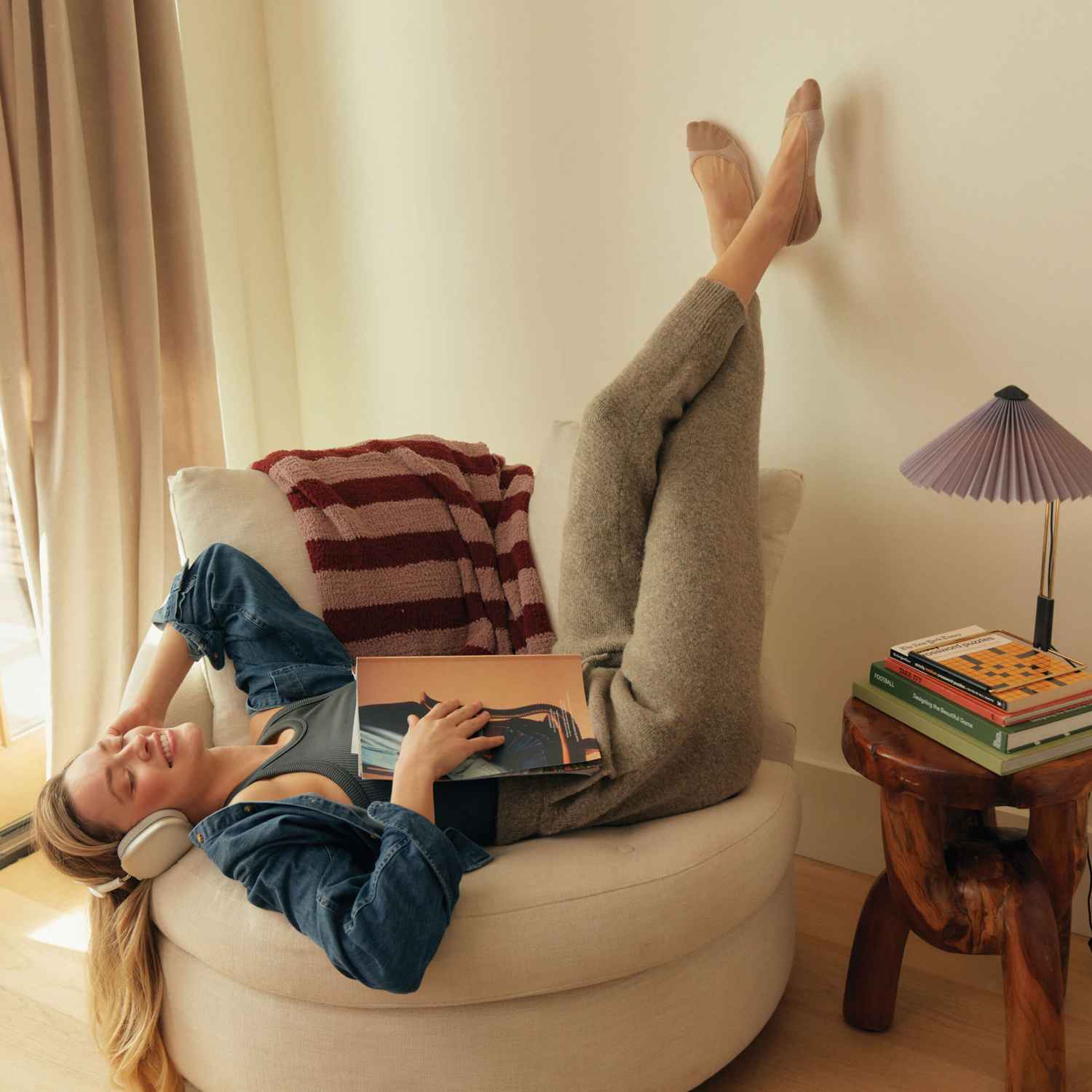 A woman lying down on a chair listening to music with her feet in the air wearing Peds no show socks.