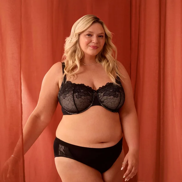 A woman wearing black intimates standing in front of red curtains