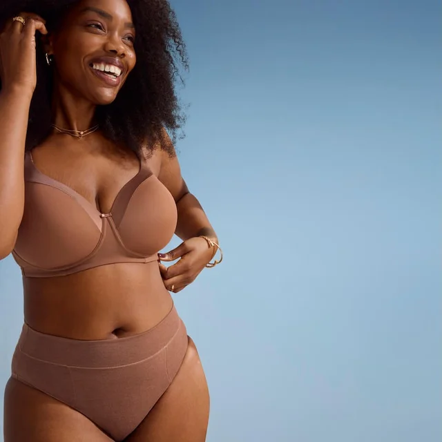 A woman wearing brown intimates in front of a blue background