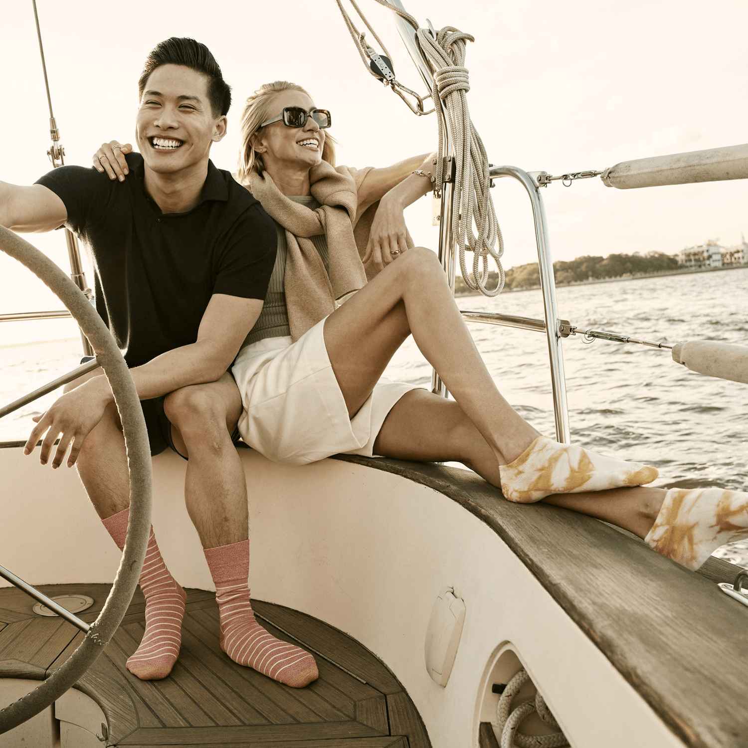 A man and woman are wearing GOLDTOE socks on a boat.