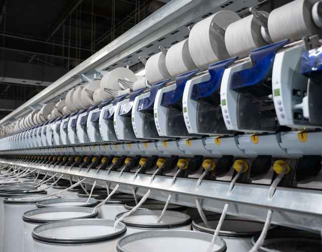 Photo of yarn spinning machines winding yarn cones.