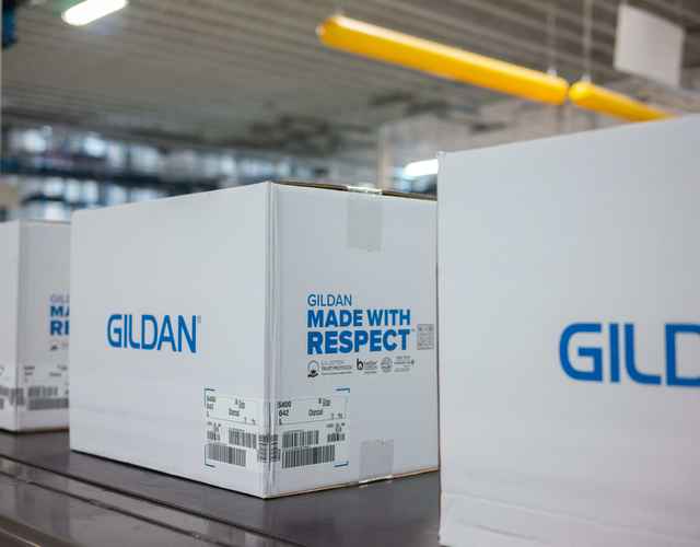 Boîtes Gildan avec le logo Made With Respect sur une ligne d'assemblage dans un centre de distributi