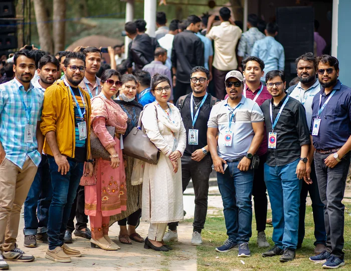 A group of employees from Bangladesh are at an employee engagement outside smiling at the camera.