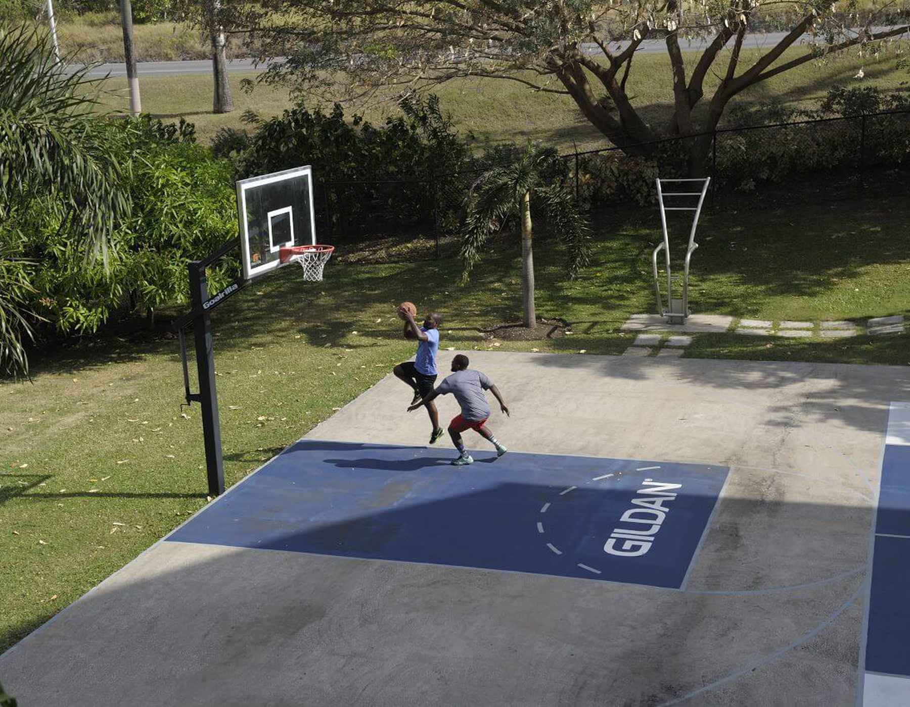 Two men are playing basketball on Gildan’s basketball court outside our office in Barbados.