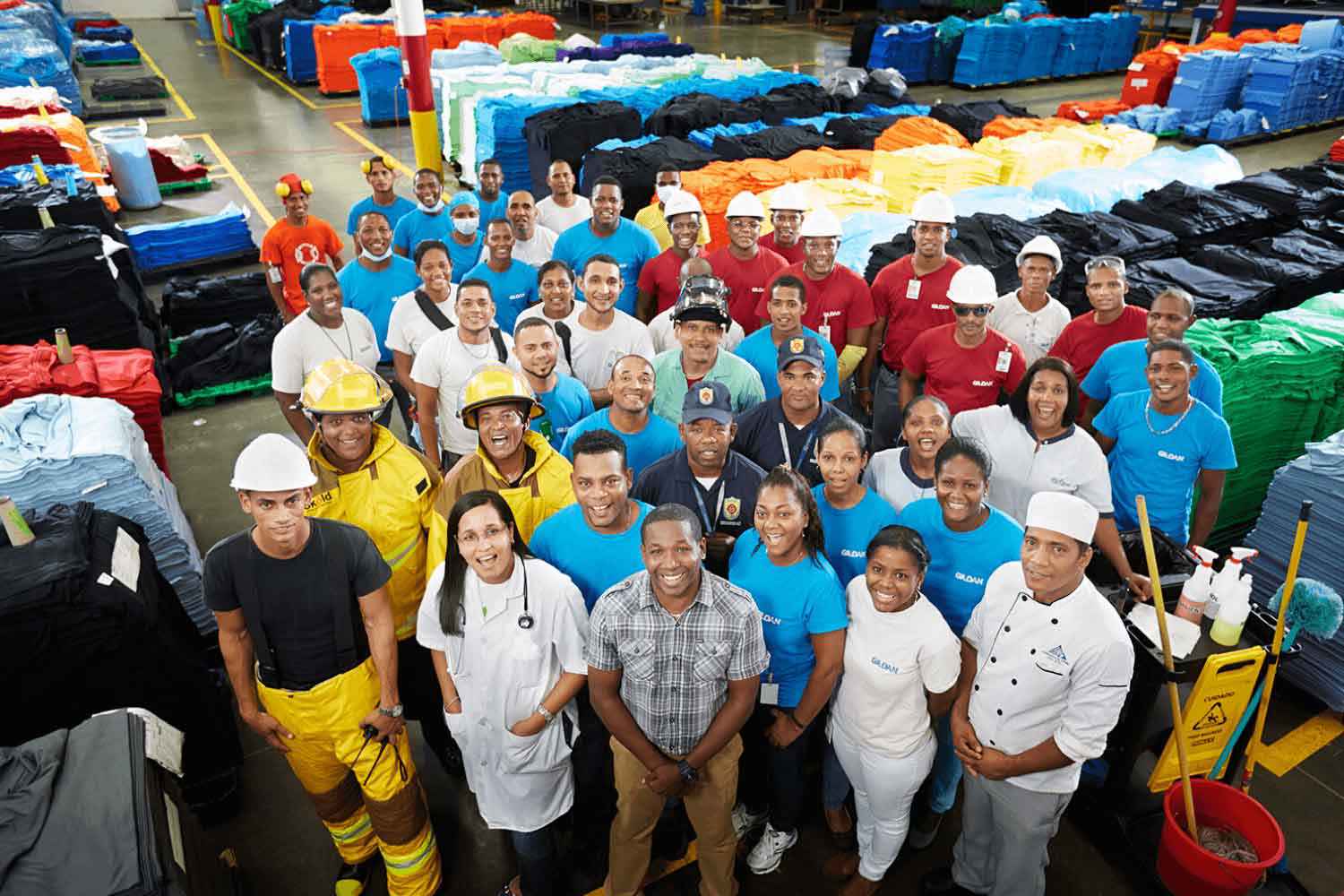 Employees in the Dominican Republic are in a large group smiling and looking up at the camera.