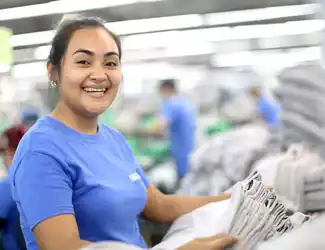 Une employée de Gildan couture sourit à la caméra.