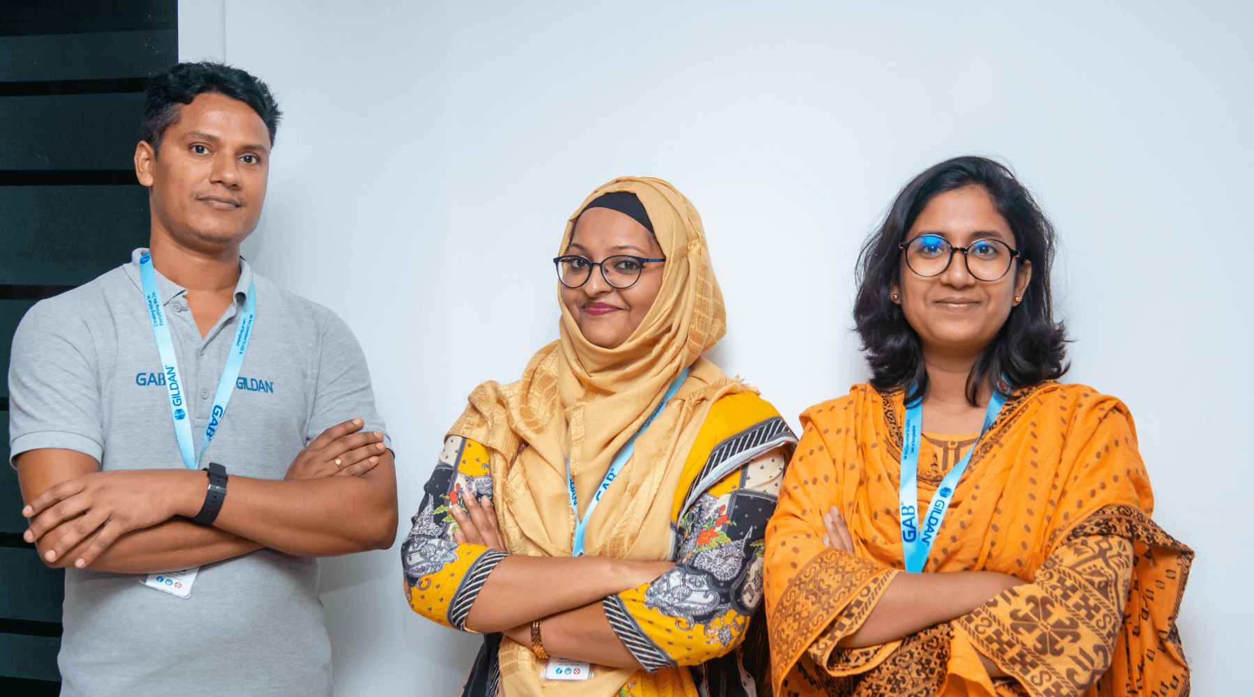 Trois employés de Gildan au Bangladesh croisent les bras et sourient à la caméra.