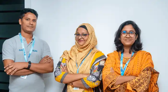 Three Gildan employees from Bangladesh are crossing their arms and smiling at the camera.