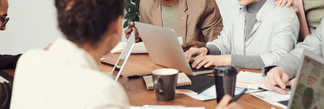 Office employees are sitting at a desk and working together.