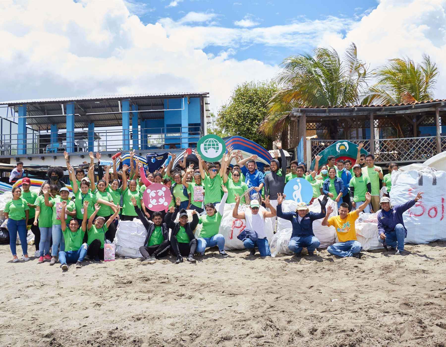 Employees from Nicaragua are standing on the beach and smiling after cleaning up.
