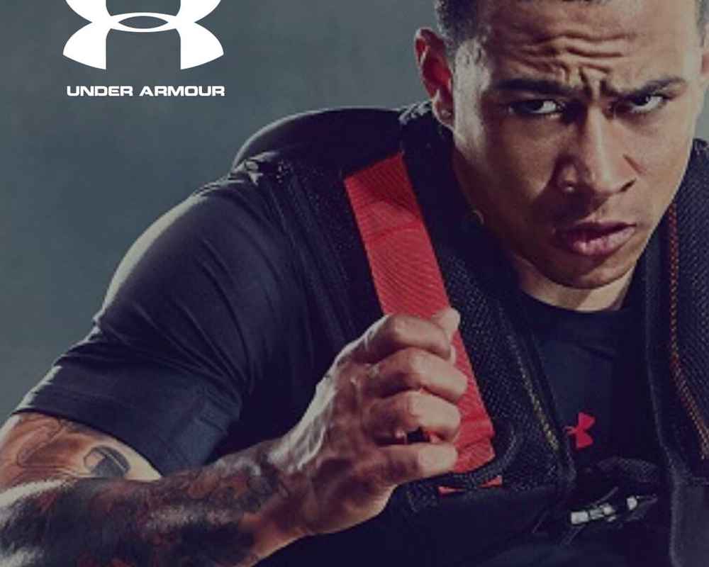 A man is carrying a black and red bag on his back with the Under Armour™ logo overlayed on the image