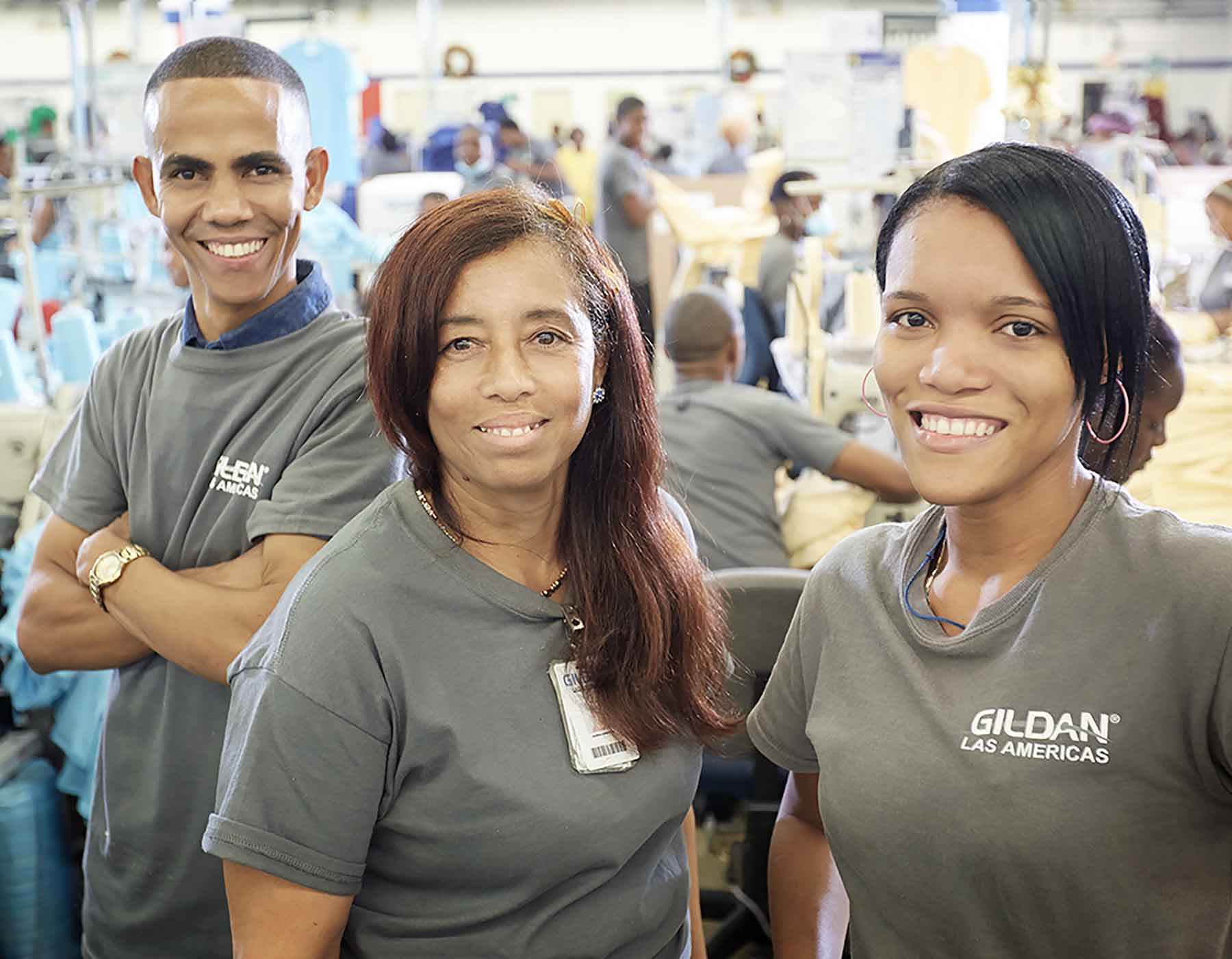 Three Gildan sewing employees from Las Americas, Dominican Republic, are smiling at the camera.