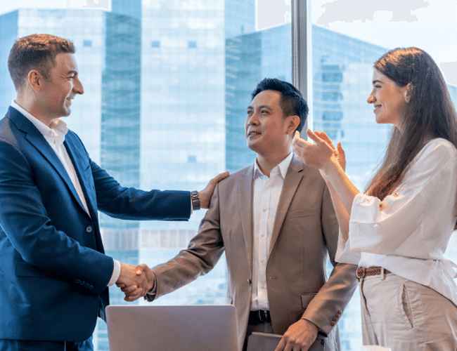 Trois employés de Singapour se trouvent dans un bureau en hauteur et se serrent la main en souriant.