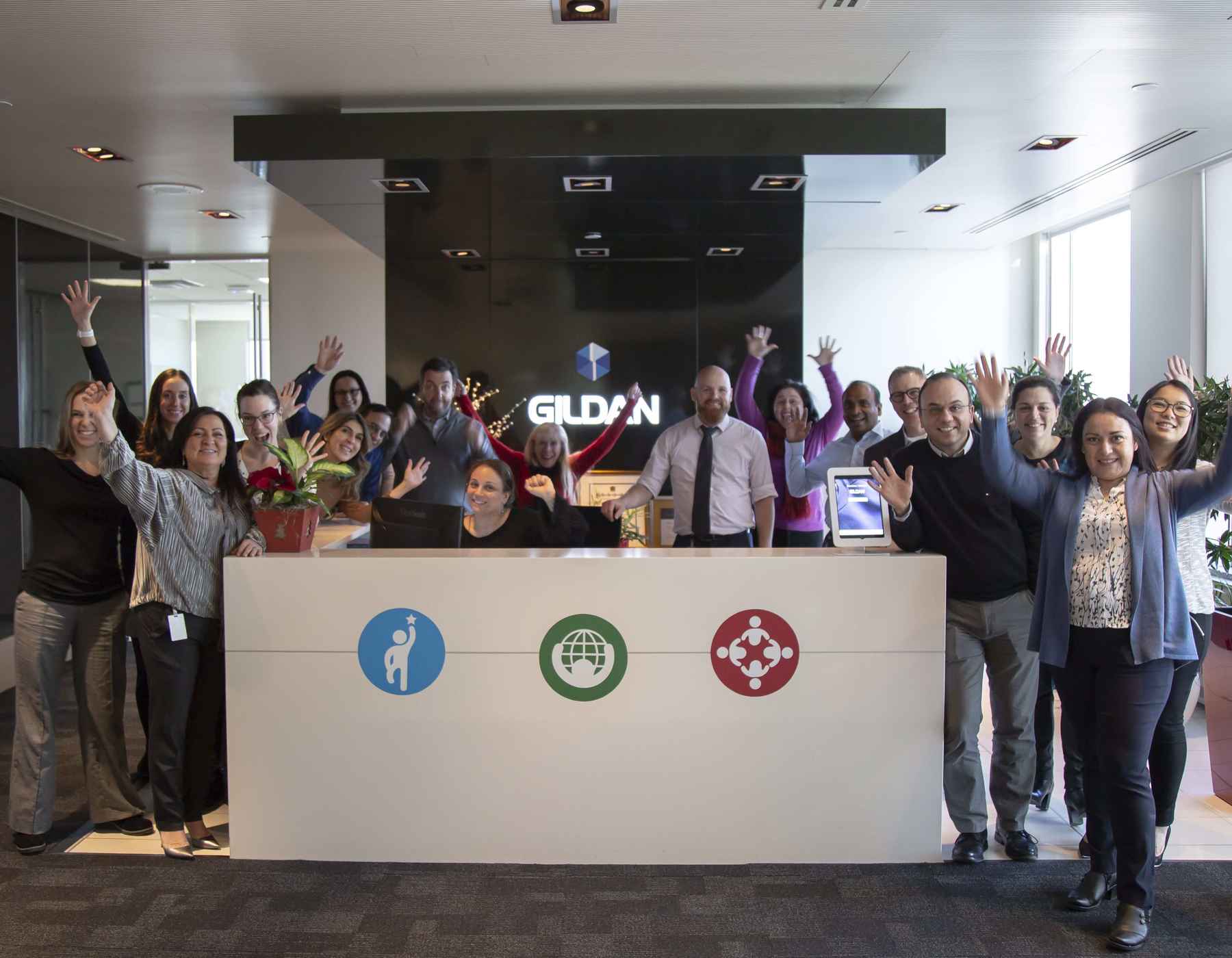 Employees are smiling and raising their hands in the air at the front desk.