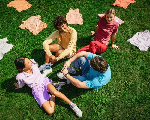 Two women and two men are lying down wearing pink Comfort Colors sweaters smiling.