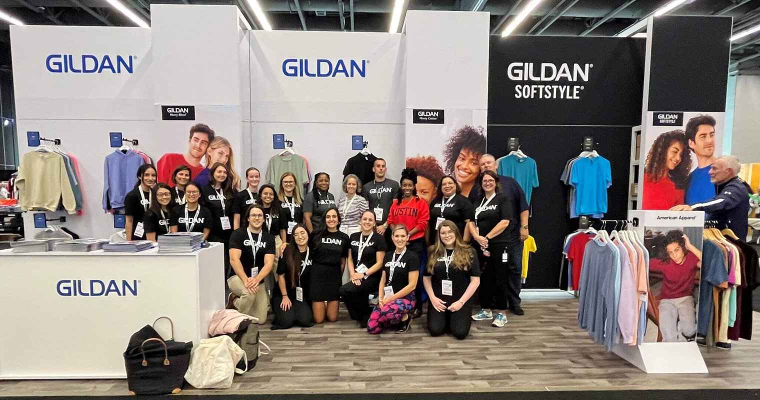 Employees from Gildan’s Head Office in Montreal are smiling at the camera at a Tradeshow event.