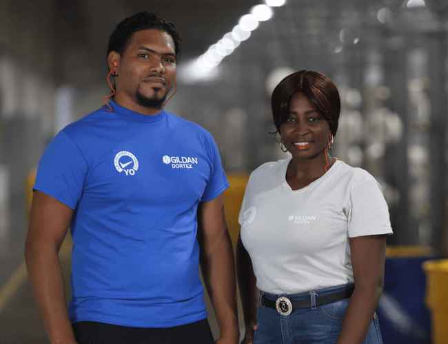 A man and women wearing Gildan t-shirts are in the textile facility in the Dominican Republic