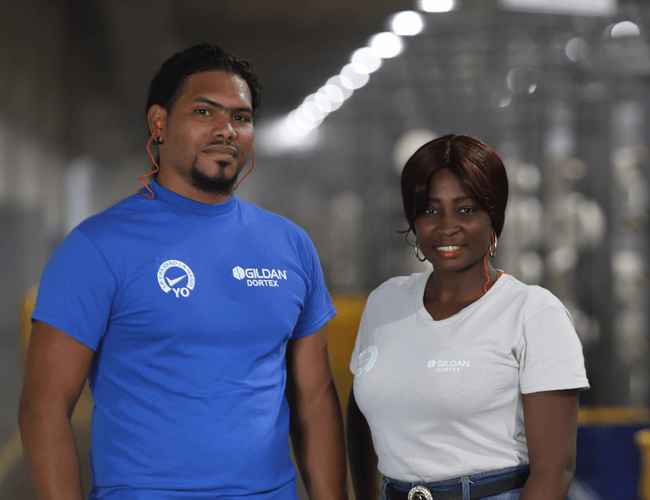 Un hombre y una mujer con camisetas Gildan en la planta textil de la República Dominicana