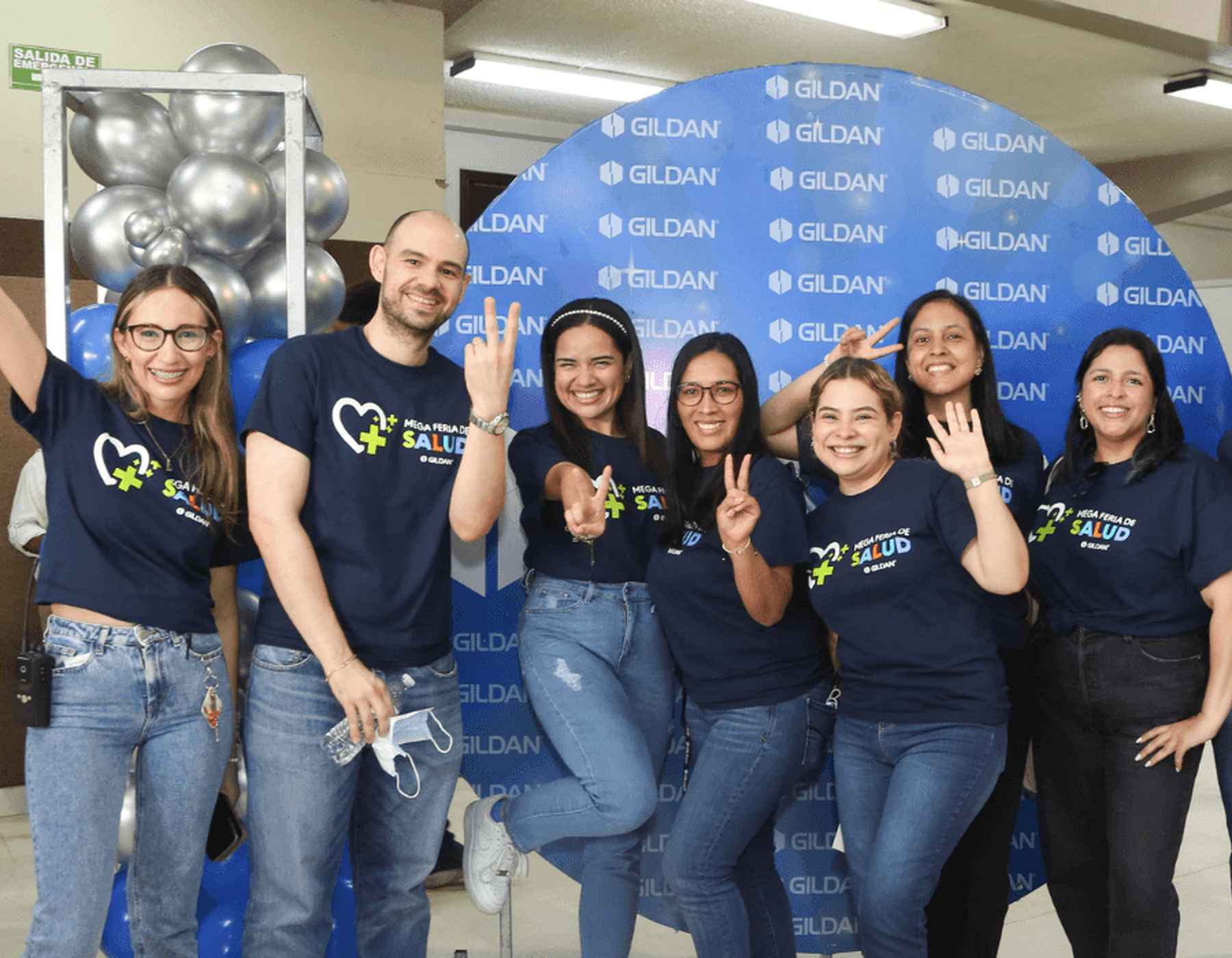 Siete empleados de Gildan sonríen llevando camisetas de Gildan a juego.