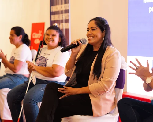 A group of children and Gildan employees in Honduras are smiling together while holding a trophy.