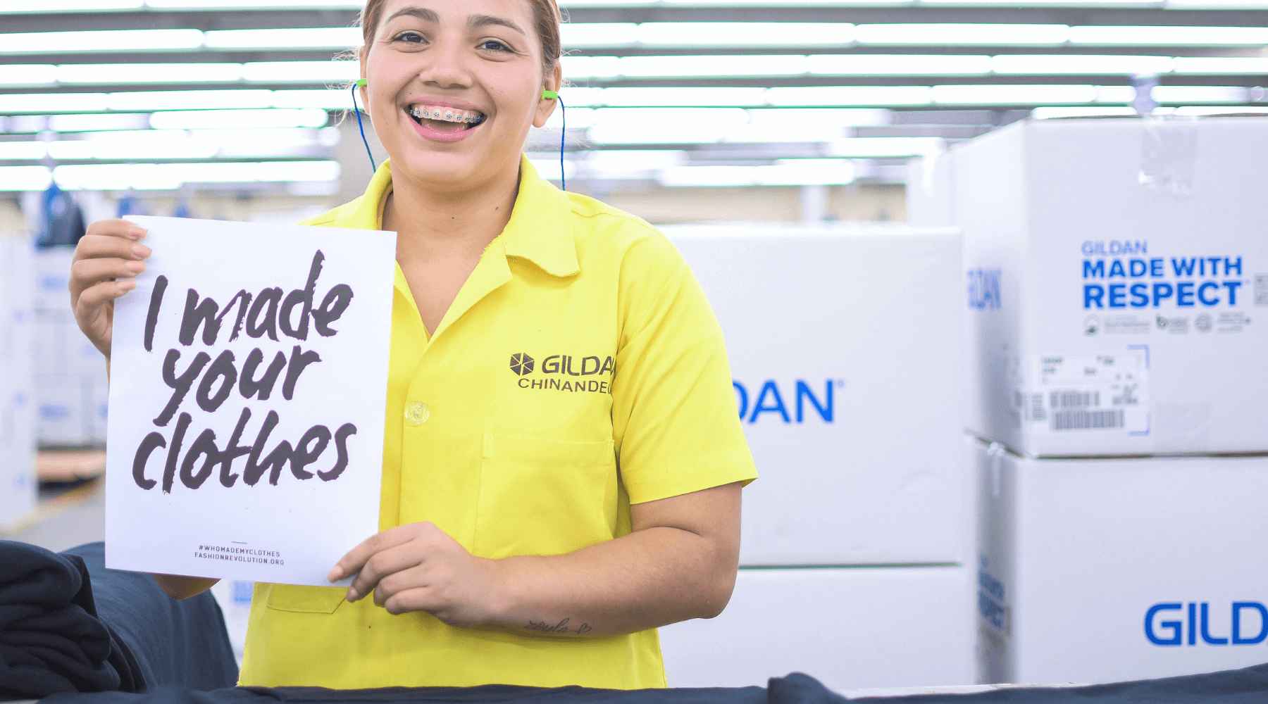 Mariela is smiling and holding a sign that reads “I made your clothes”.
