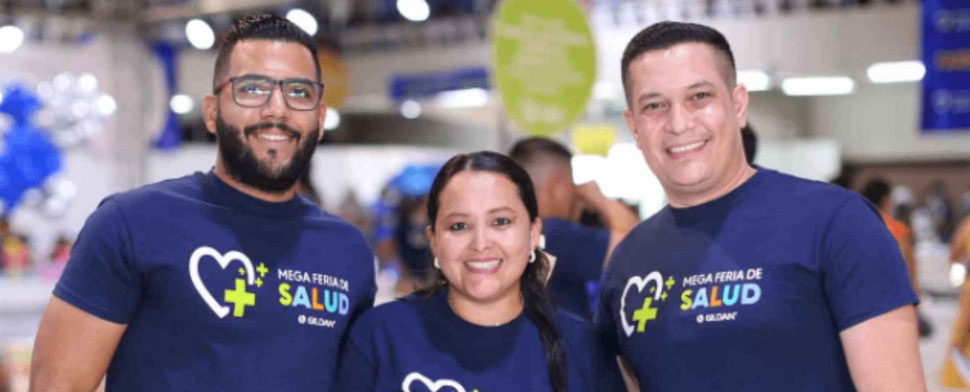 Tres empleados llevan camisetas Gildan azul marino y sonríen a la cámara.