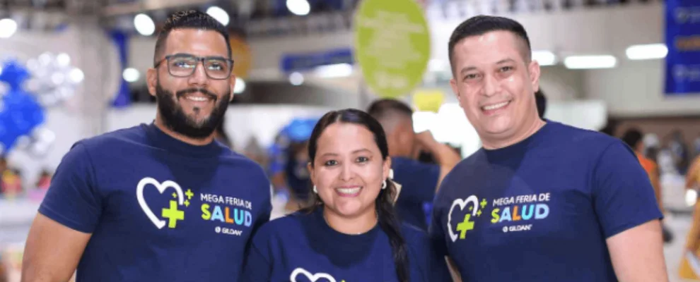 Tres empleados llevan camisetas Gildan azul marino y sonríen a la cámara.