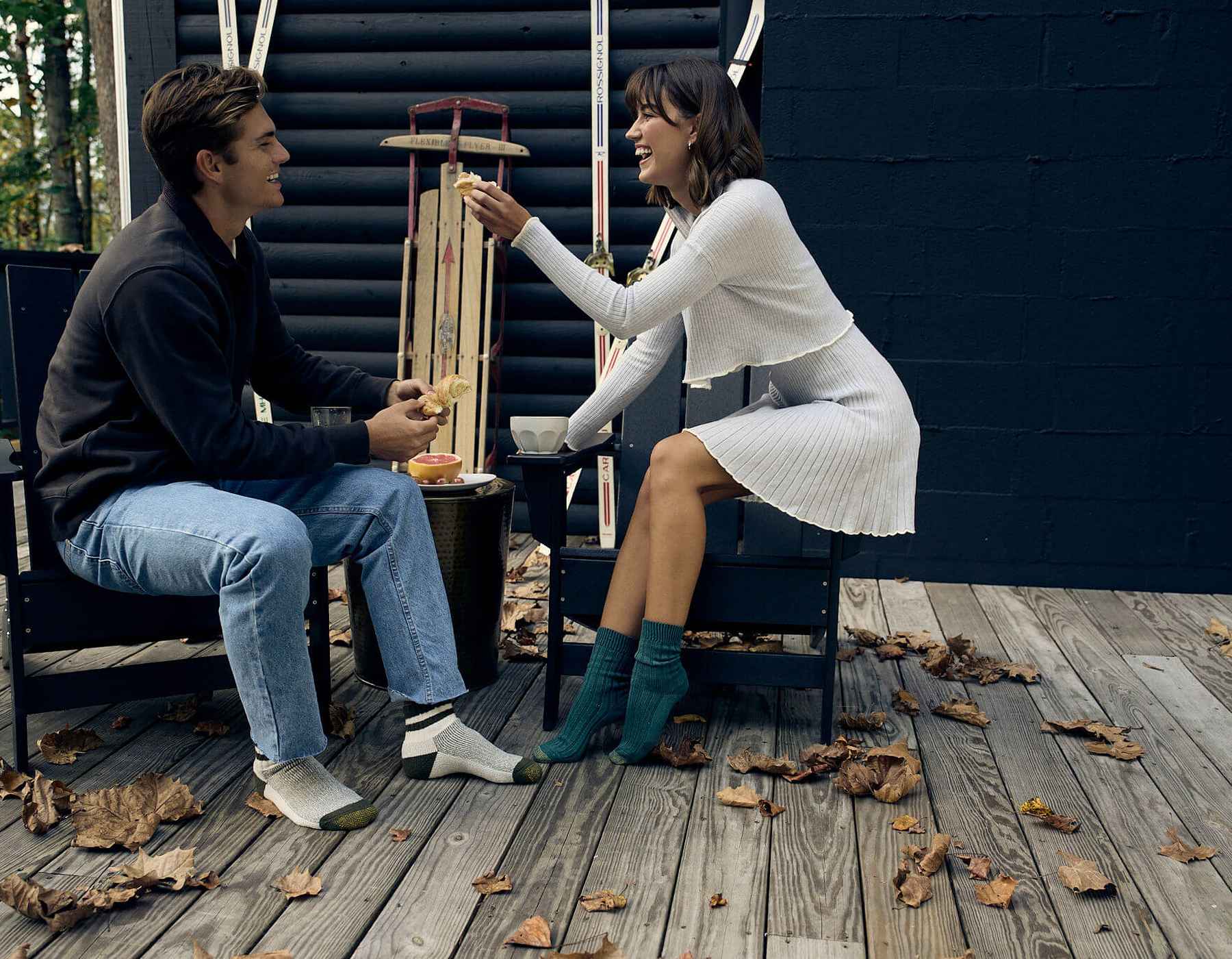 A woman and a man are sitting outside wearing GOLTOE socks eating and smiling.