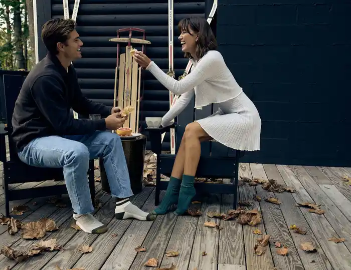 A woman and a man are sitting outside wearing GOLTOE socks eating and smiling.
