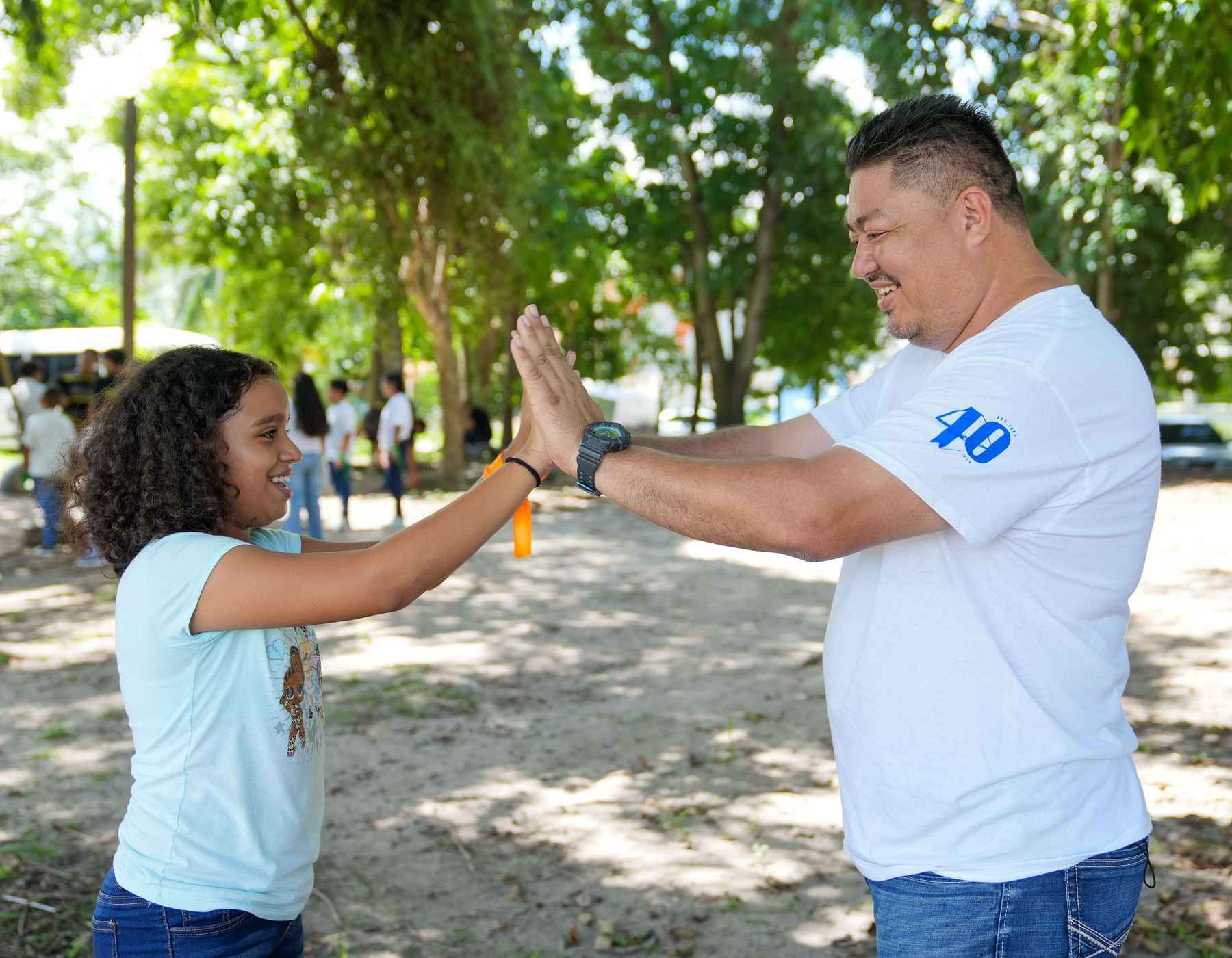 A Gildan employee is playing with a child outside at a Gildan event.