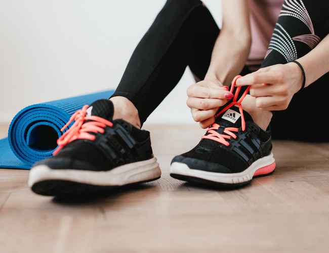 A woman is lacing up her running shoes.