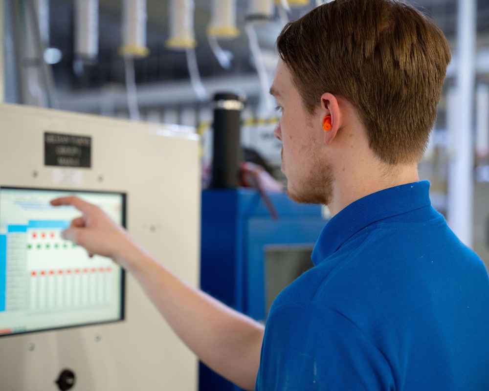 An employee at Mocksville yarn spinning facility adjusting machine automation.