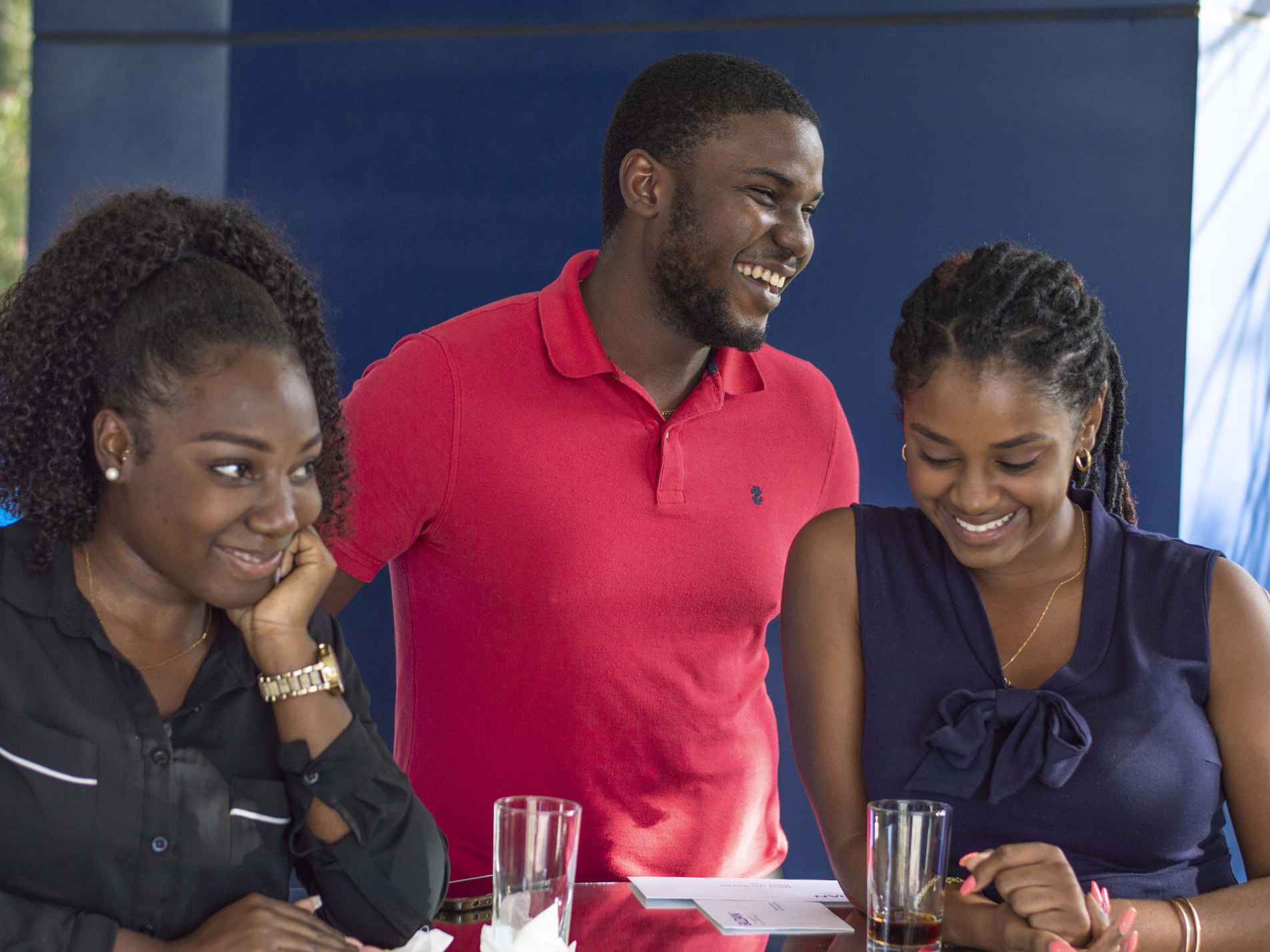 Three Gildan interns are laughing while sitting together at a table.