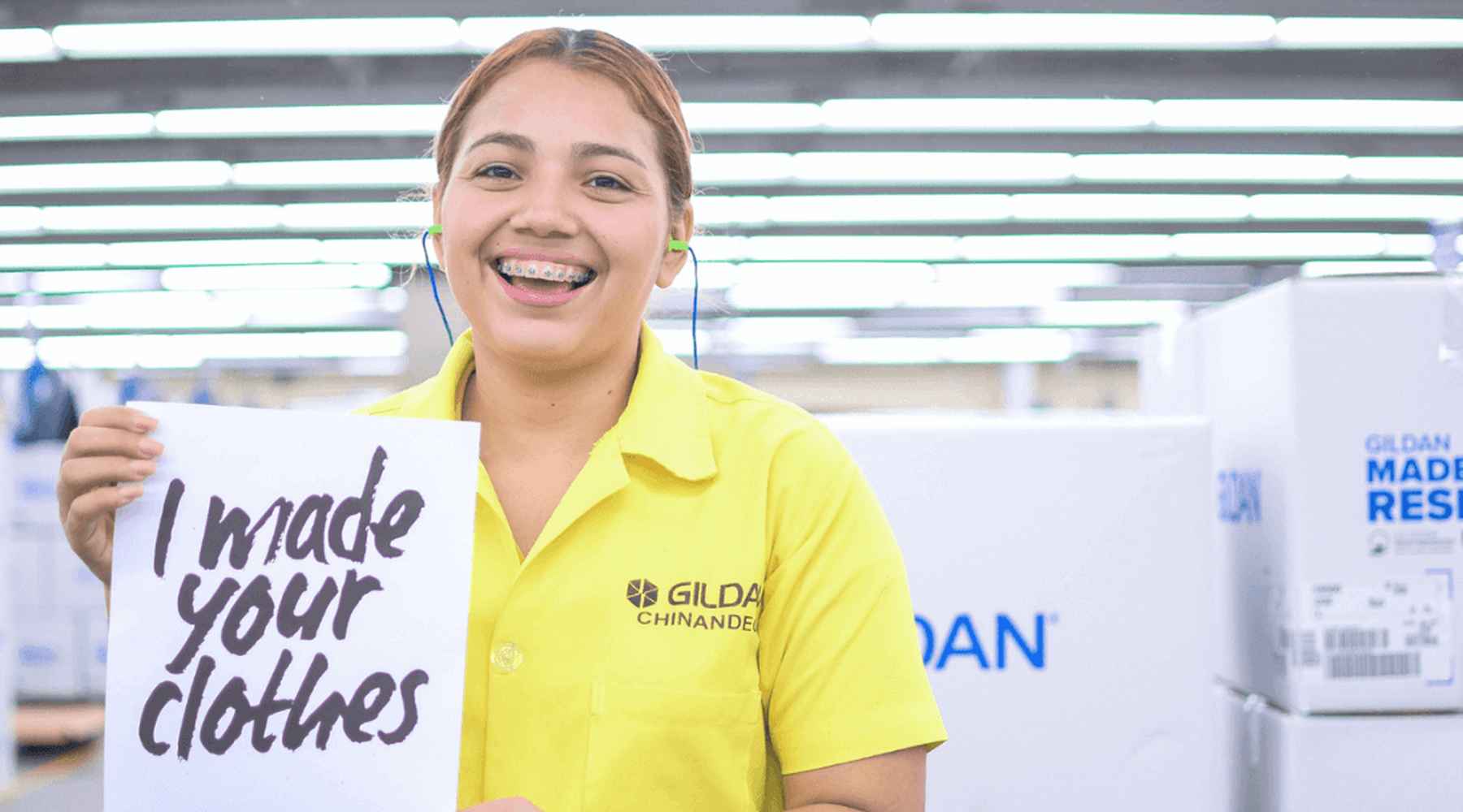 Mariela is smiling and holding a sign that reads “I made your clothes”.