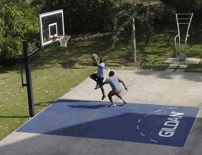 Two employees are playing basketball outside on the Gildan court in Barbados.