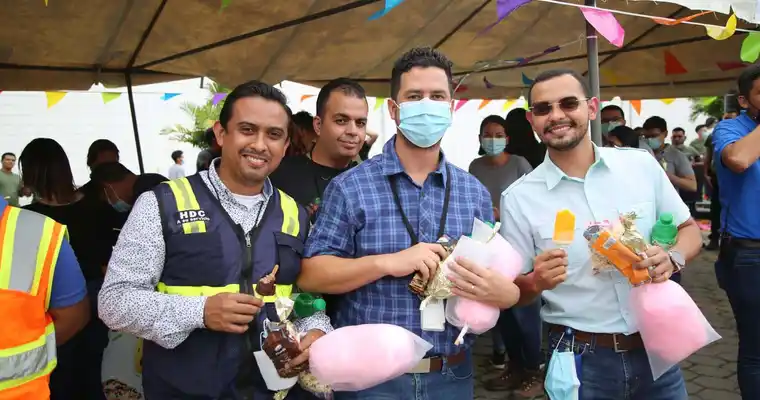 4 empleados en Honduras están sonriendo mientras sostienen algodón de azúcar y helado afuera.