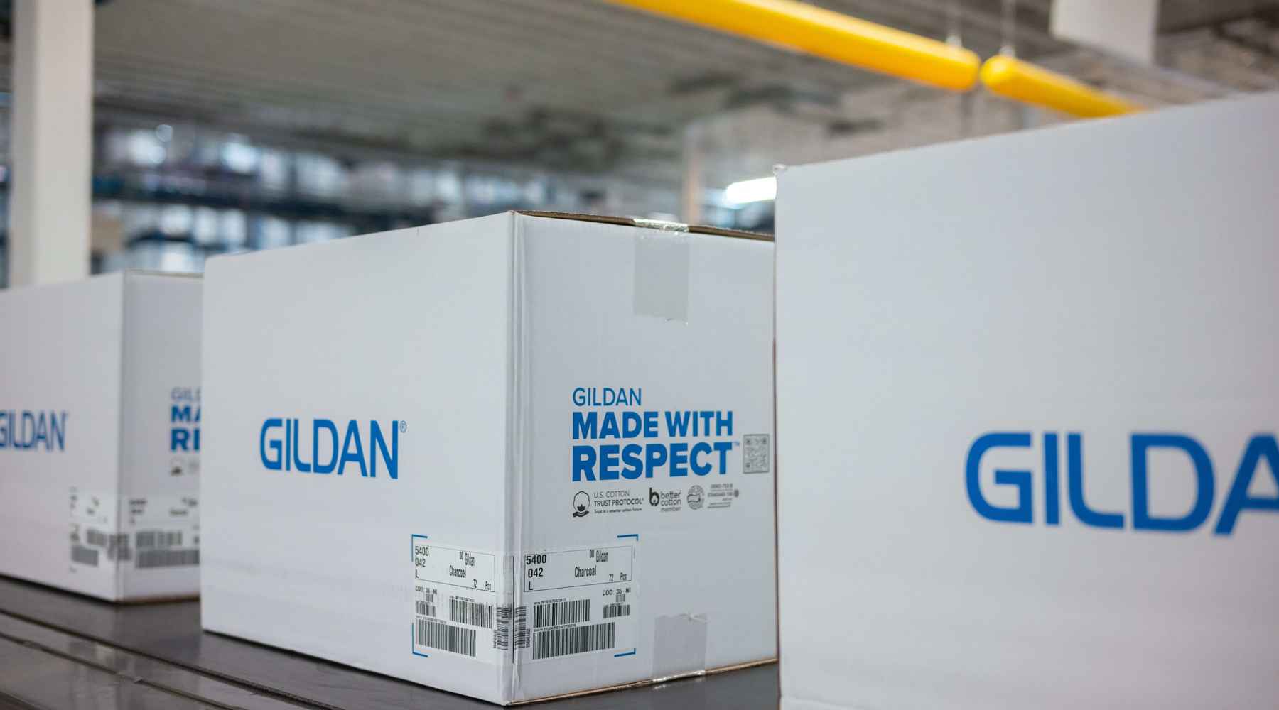 Gildan Made With Respect boxes are going down a conveyor belt.