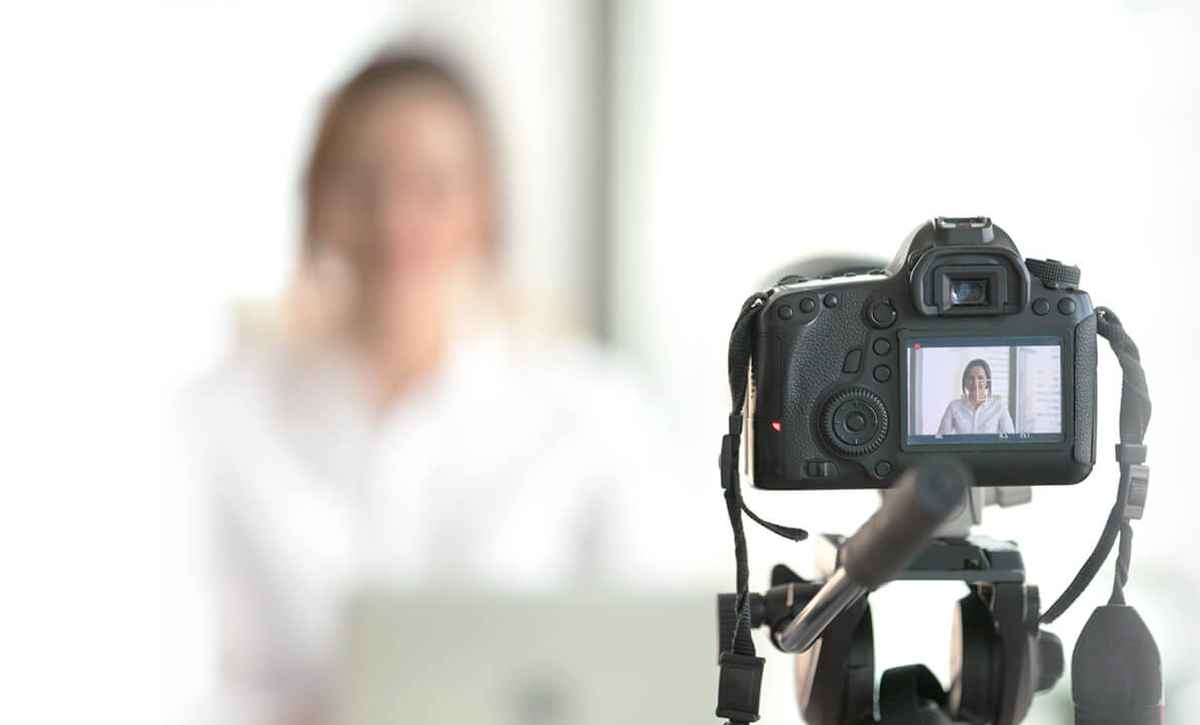 A woman has a camera setup on a tripod and is recording herself.