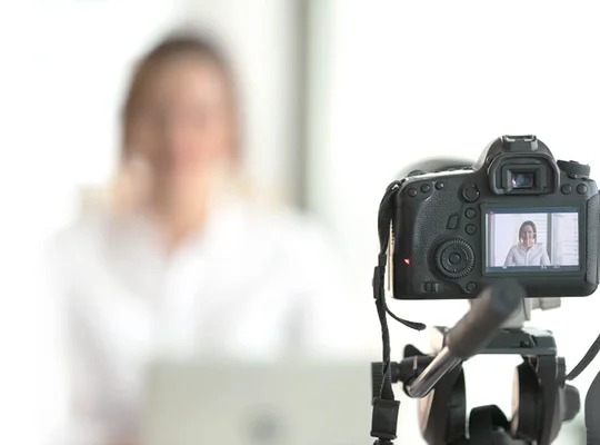 A woman has a camera setup on a tripod and is recording herself.