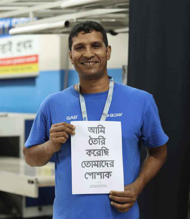 Mohammad is smiling at the camera and holding a sign that reads “I made your clothes”.