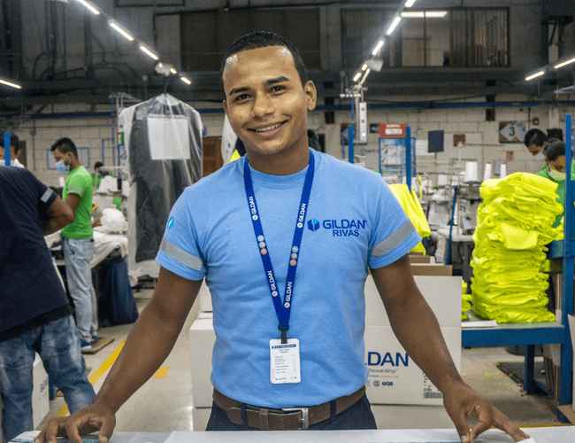 Un employé de Gildan porte un cordon et une chemise bleue de Gildan.