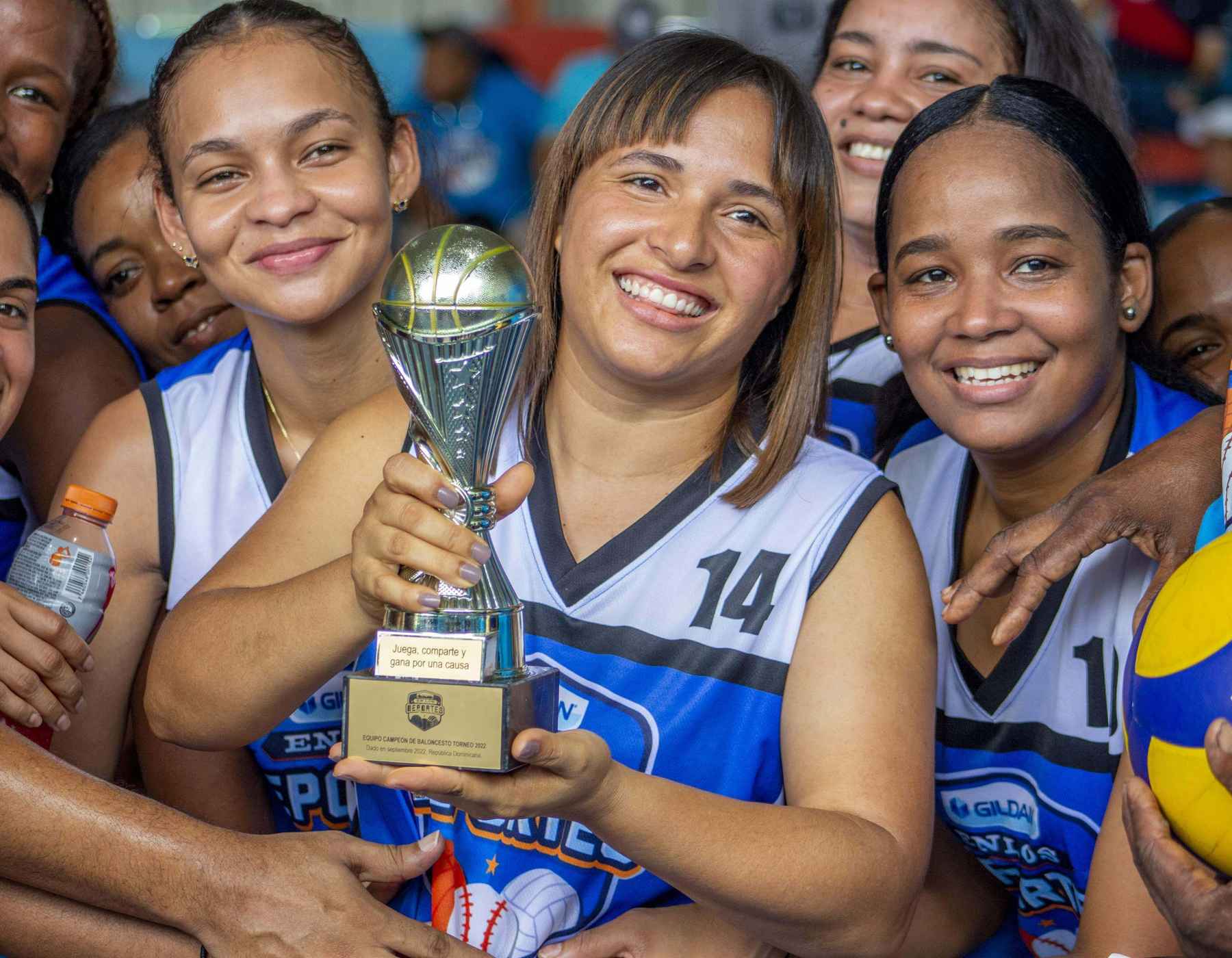 Gildan employees and holding a basketball trophy while wearing their blue and white jerseys.