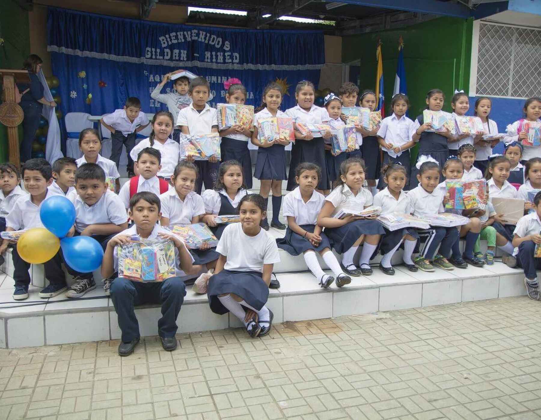 Les enfants portent des uniformes scolaires et sourient tout en tenant des fournitures scolaires.